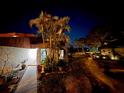 Inviting townhome exterior with lush landscaping, mature palm trees, and a well-lit walkway to the front door at 2058 Sunset Point Rd # 11, Clearwater, FL 33765