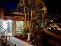 Inviting townhome exterior with lush landscaping, mature palm trees, and a well-lit walkway to the front door at 2058 Sunset Point Rd # 11, Clearwater, FL 33765