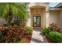 Elegant front entrance with double doors, decorative lighting, tile flooring, and meticulously maintained landscaping at 4912 Sabal Lake Cir, Sarasota, FL 34238