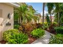Landscaped front yard featuring vibrant flowers, tropical foliage, a sidewalk, and a view of the home's facade at 4912 Sabal Lake Cir, Sarasota, FL 34238