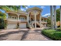 Elegant estate showcasing its grand exterior with a curved staircase and lush landscape at 975 Whitakers Ln, Sarasota, FL 34236