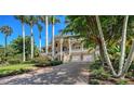 Beautiful home exterior with lush greenery, stately palm trees, and a circular driveway at 975 Whitakers Ln, Sarasota, FL 34236