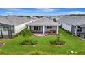 Aerial view of backyard featuring a covered patio, lush green lawn, and meticulous landscaping at 10394 Abaco Falls Dr, Englewood, FL 34223