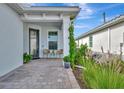 Inviting front porch featuring a seating area and manicured landscaping with climbing vines at 10394 Abaco Falls Dr, Englewood, FL 34223