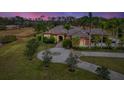 Stunning luxury property with a circular driveway, tropical plants, and a peaceful setting at dusk at 24705 83Rd E Ave, Myakka City, FL 34251