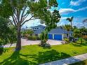 Beautiful home with a blue tiled roof, bright blue garage doors and lush green lawn at 4307 Camino Real, Sarasota, FL 34231
