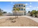 Coastal home featuring a garage, gravel landscaping, and two palm trees in the front yard at 4717 Lemon Bay Dr, Venice, FL 34293