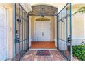 Open security gate revealing the front door, red tile entrance, and 'Welcome' mat at 585 Khyber Ln, Venice, FL 34293