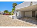 View of the carport with brick-paved driveway and tropical landscaping at 750 Bayport Way # 750, Longboat Key, FL 34228