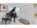 Elegant entryway featuring a grand piano, decorative glass block window, and storage closet at 8142 Misty Oaks Blvd, Sarasota, FL 34243
