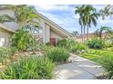 Landscaped front yard with lush tropical plants and fountain create a welcoming entrance to this bright home at 8142 Misty Oaks Blvd, Sarasota, FL 34243