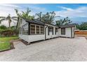 Side view of a well-maintained home showcasing the gravel yard, black trim, and white siding in a charming outdoor setting at 1016 38Th W St, Bradenton, FL 34205