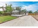 Back view of a charming home with gravel driveway and black trim, set against a blue sky, evoking a welcoming atmosphere at 1016 38Th W St, Bradenton, FL 34205