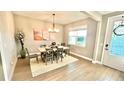 Elegant dining room with wood floors, modern chandelier, area rug, and access to the front entrance at 13422 Flat Woods Ter, Bradenton, FL 34211