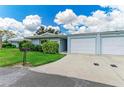 Charming home featuring lush landscaping, a blue exterior, a paved drive leading to the one-car garage at 1364 Westport Ln # 1403, Sarasota, FL 34232