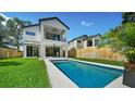 Home back view showcasing a sparkling pool, lush green lawn, and modern architectural design at 2249 Oak Terrace Ter, Sarasota, FL 34231
