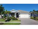 Charming single-story home showcasing a well-manicured lawn, colorful flowerbeds, and a covered front porch at 26017 Seastone Dr, Englewood, FL 34223