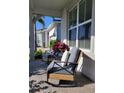 Cozy front porch with rocking chairs and decorative pillows next to a large window and blossoming flowers at 26017 Seastone Dr, Englewood, FL 34223