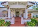 Inviting entryway featuring a brick path, white columns, and lush garden with floral accents at 4636 Pine Harrier Dr, Sarasota, FL 34231