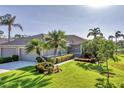 A beautifully landscaped single-story home showcasing a well-kept lawn, and mature palm trees at 5217 Chase Oaks Dr, Sarasota, FL 34241