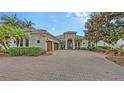 Stately home with a lush, landscaped front yard, mature tree and circular driveway at 6919 Dominion Ln, Lakewood Ranch, FL 34202