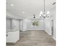 Bright living room with wood floors, neutral walls, modern light fixtures, and natural light from the large window at 8304 Fishhawk Ave, New Port Richey, FL 34653