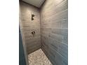 The shower features stylish gray tiling with stone pebble accents on the floor and modern fixtures at 12127 Storke Ave, Port Charlotte, FL 33981
