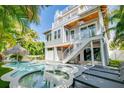 A backyard paradise with sparkling pool, hot tub, and outdoor lounge area surrounded by lush tropical foliage at 212 72Nd, Holmes Beach, FL 34217