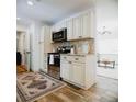 Stylish kitchen featuring stainless steel appliances, white cabinetry, and wood flooring at 2300 Stratford Dr, Sarasota, FL 34232