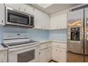 Bright kitchen with white appliances including a microwave and refrigerator with white cabinets at 3610 54Th W St # B4, Bradenton, FL 34209