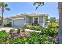 Single Gathering house with a gray garage door, surrounded by beautiful landscaping and plants at 4740 105Th E Ave, Parrish, FL 34219