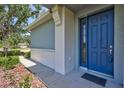 Close-up of a blue front door with welcome mat, showing a covered entry and manicured landscaping at 4740 105Th E Ave, Parrish, FL 34219