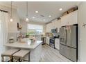Modern kitchen features white cabinets, stainless steel appliances, and an island with a breakfast bar at 5155 78Th St E Cir, Bradenton, FL 34203