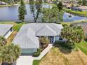 A nice aerial view of this charming home showing landscaping, lawn, nearby lake, and the home's roof at 5596 Sable Trace Dr, North Port, FL 34287