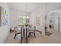 Elegant dining room featuring a glass table, striped chairs, chandelier, and natural light from the large window at 750 Anna Hope Ln, Osprey, FL 34229