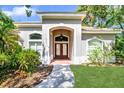 Elegant home entrance with a brick pathway, arched doorway, and well-maintained landscaping at 104 Park Trace Blvd, Osprey, FL 34229