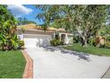 Beautiful home featuring a manicured lawn, mature trees, and a brick-lined driveway at 104 Park Trace Blvd, Osprey, FL 34229