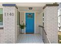 Inviting entryway featuring a vibrant blue door, decorative tile flooring, and classic brick columns at 1140 Oak Ne St, St Petersburg, FL 33701