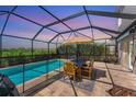 Relax by the sparkling pool in the screened enclosure, complete with dining area and lush greenery at 13013 Oak Hill Way, Parrish, FL 34219