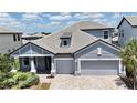 Close up shot of the exterior of the house, showcasing a two car garage, gray paint, and a paver driveway at 16905 Sweetwater Village Dr, Bradenton, FL 34211