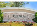 Close-up of The Isles on Palmer Ranch sign enhanced by colorful flowers and greenery at 1831 Burgos Dr, Sarasota, FL 34238