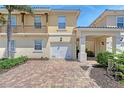Townhome featuring an attached garage with brick paver driveway and well-maintained landscaping at 1831 Burgos Dr, Sarasota, FL 34238