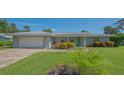 Inviting single-story home featuring lush green lawn, colorful flowerbeds, and a bright green front door at 1857 Jasmine Dr, Sarasota, FL 34239