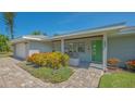 Inviting front porch with seating area, vibrant flowers, and a distinctive green front door at 1857 Jasmine Dr, Sarasota, FL 34239