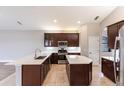 Modern kitchen featuring dark wood cabinets, stainless steel appliances, island, and tile flooring at 235 Dahlia Ct, Bradenton, FL 34212