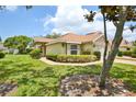 Well-maintained single-story home with lush green lawn, mature shrubs, and a brick-paved walkway at 2407 New Haven Cir, Sun City Center, FL 33573