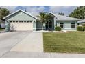 Charming single-story home with a well-maintained lawn, light green exterior, and two-car garage at 245 Woodingham Trl, Venice, FL 34292