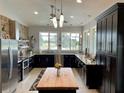 Modern kitchen with dark cabinetry, stainless steel appliances, and a large island overlooking backyard at 48 Lark Dr, Placida, FL 33946