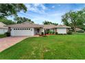 Single-Gathering home with a tile roof, green lawn, brick-accented front, and a two-car garage at 5705 Garden Lakes Majestic, Bradenton, FL 34203