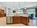 Modern kitchen featuring wood cabinetry, stainless steel dishwasher, and a counter overlooking the living space at 6240 Falcon Lair Dr, North Port, FL 34287